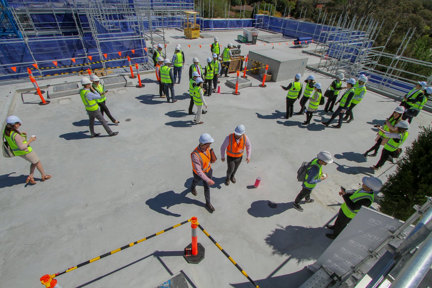 Construction professionals inspect rooftop building work with scaffolding.