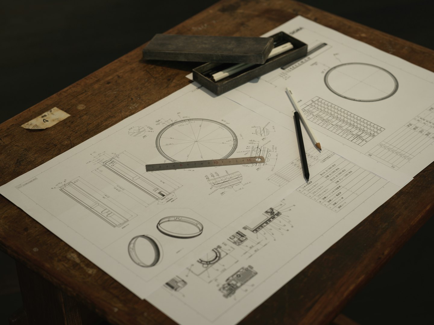 Engineering blueprints and tools on a wooden desk.